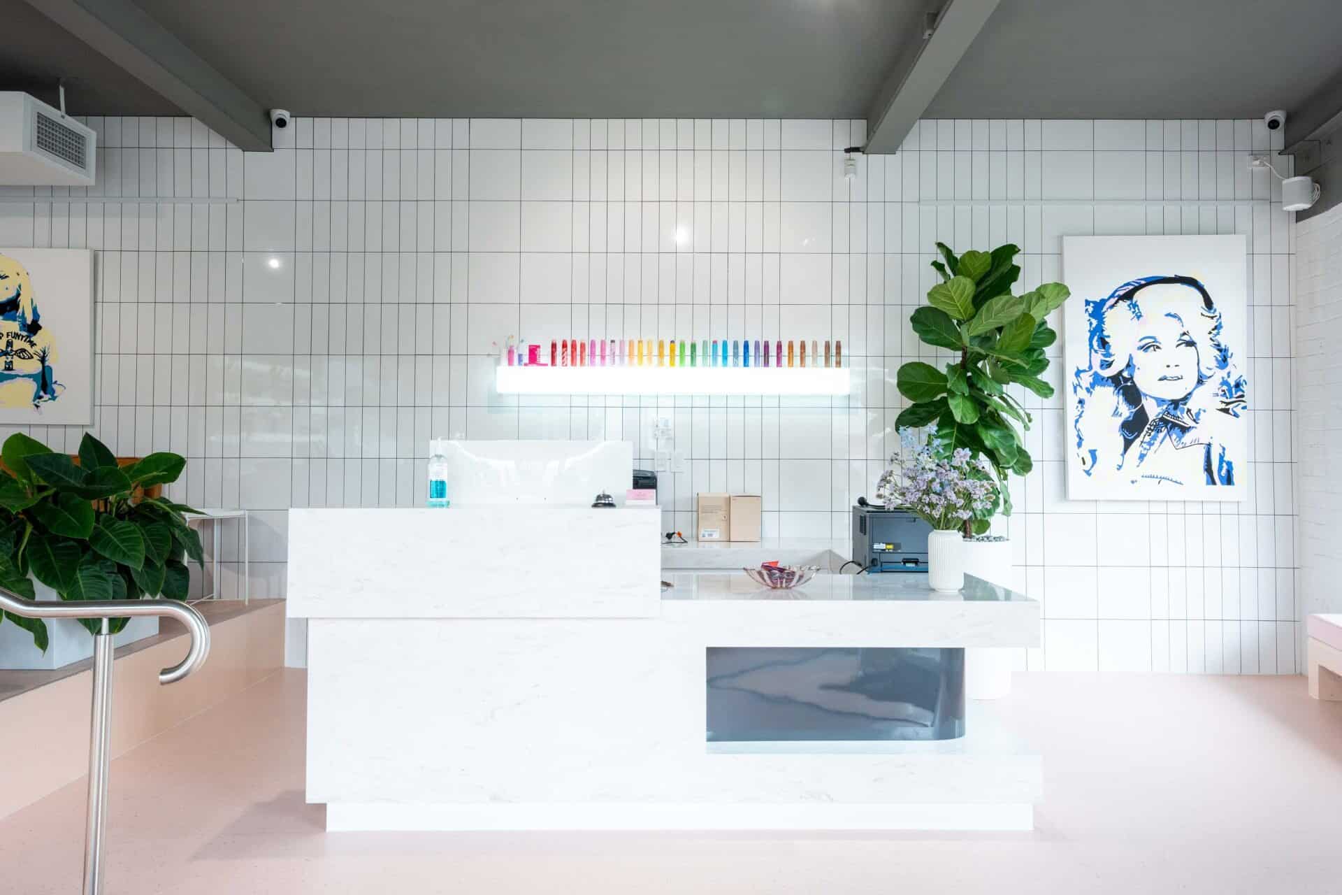 The marble reception desk, backed by a lit shelf of coloured toothbrushes and a fiddle-leaf fig