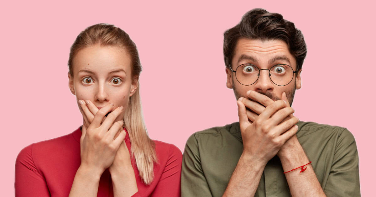 A man and woman covering their mouths with their hands.